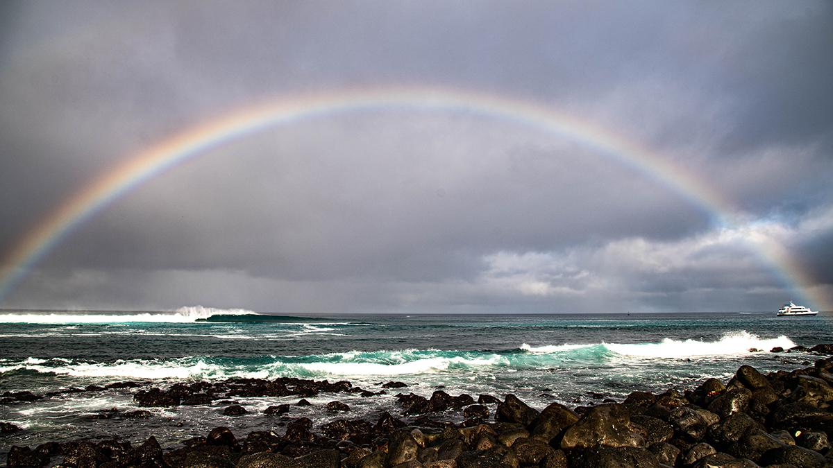 Rainbow stretching across Punta Carola Beach in San Cristobal, Galapagos.